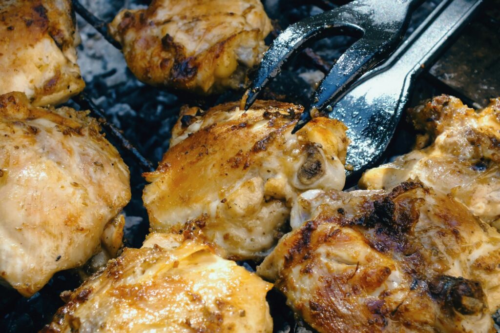 a close up of chicken on a grill with a fork
