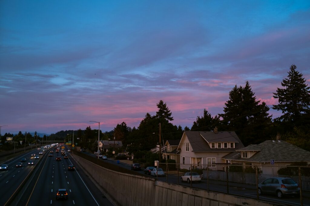 a city street at dusk with a pink sky
