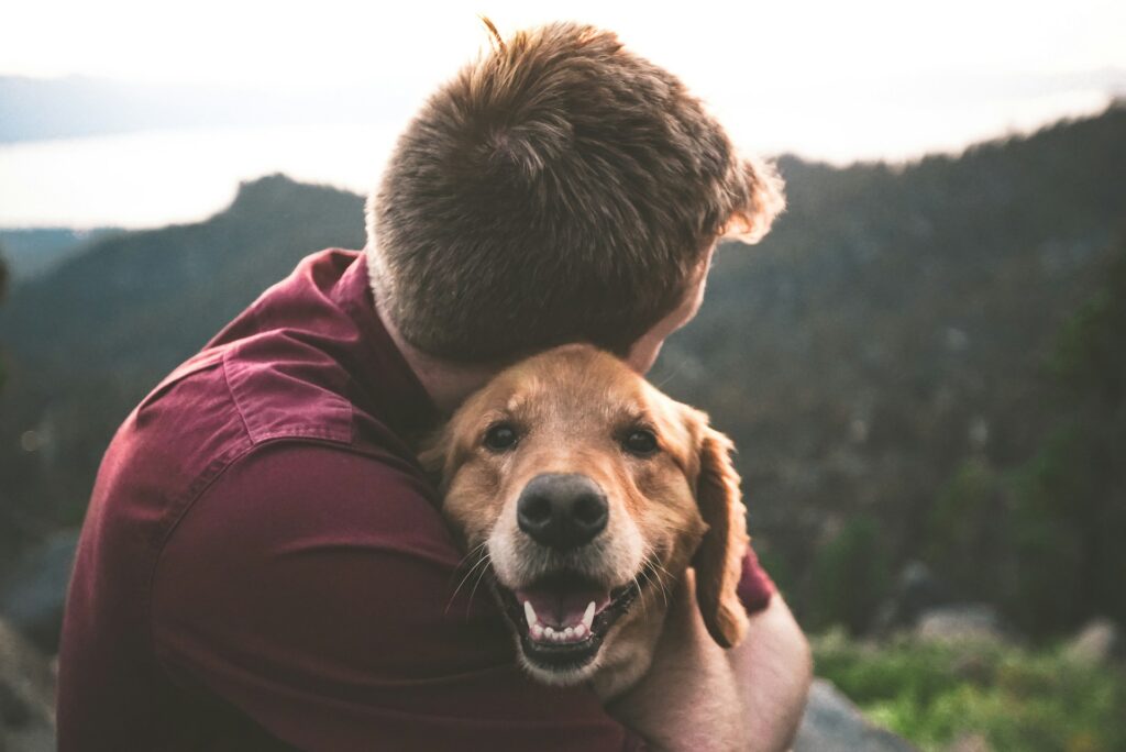 photo of man hugging tan dog
