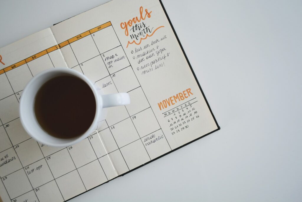 white ceramic mug with coffee on top of a planner
