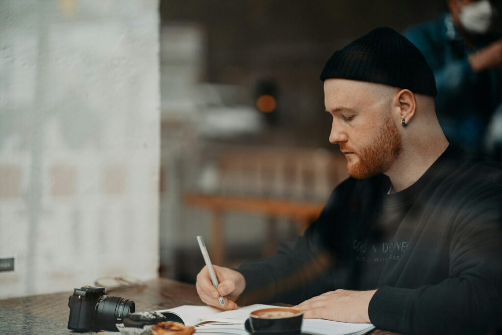 a man sitting at a table writing on a piece of paper
