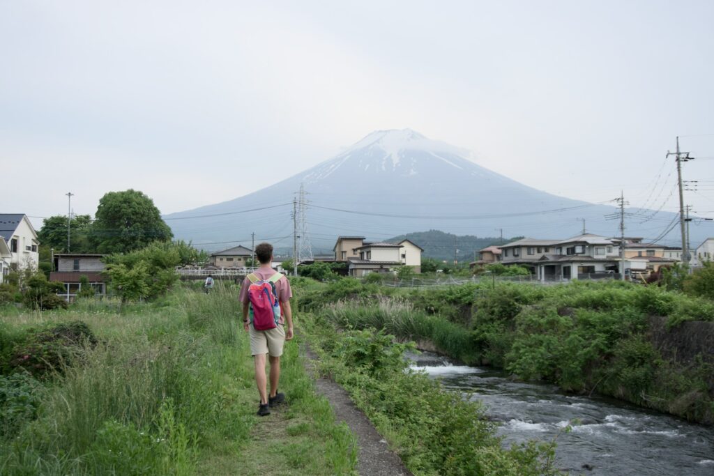 a man with a backpack walking down a path next to a river
