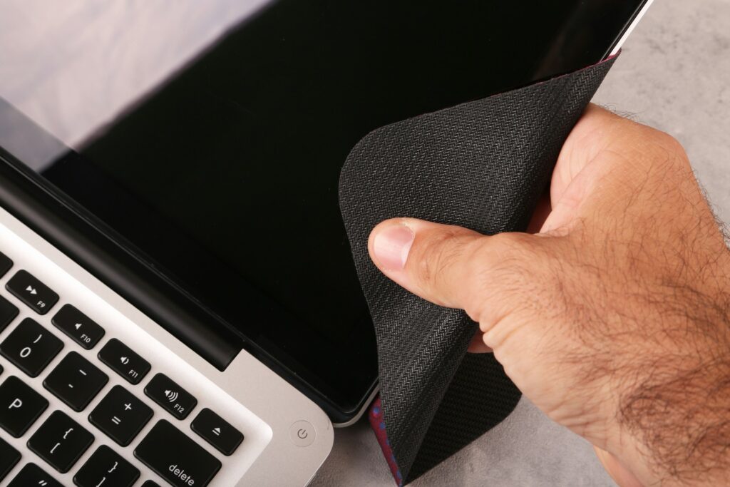 a hand holding a cloth over a laptop
