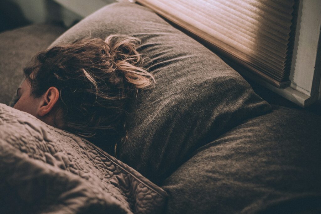 woman sleeping on bed under blankets
