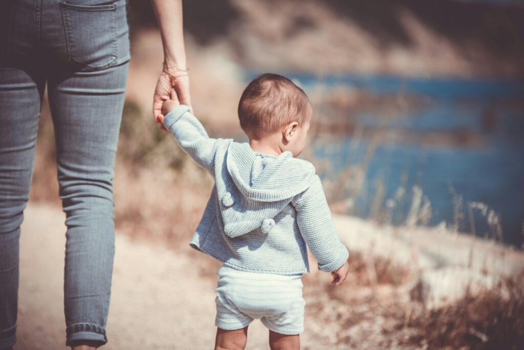 toddler's walking on the seashore with adult
