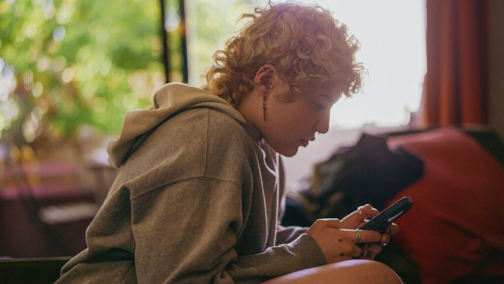 Portrait of a nonbinary autistic person using their mobile phone indoors
