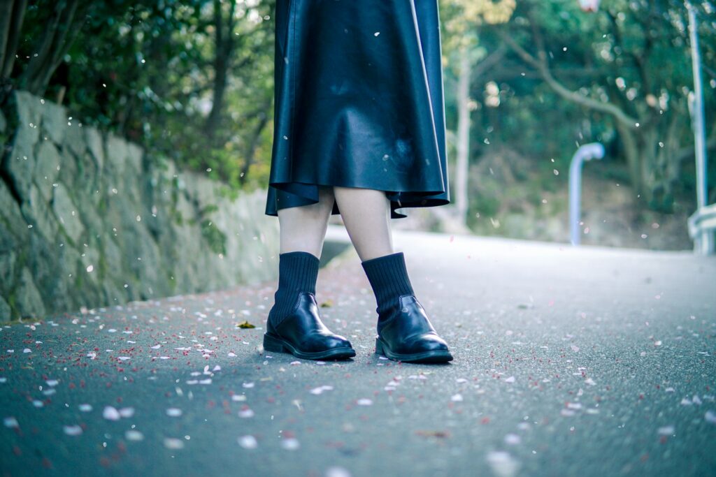 person in black rain boots walking on road during daytime
