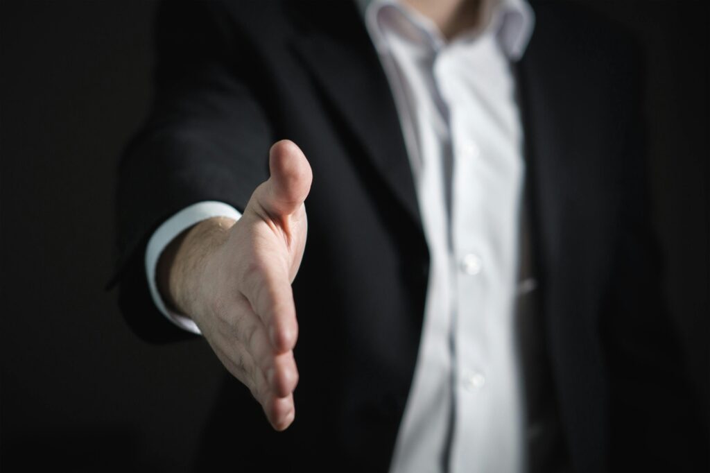 Professional in dark suit extending hand for handshake.