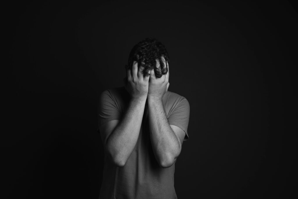 Person covering face with both hands in distress.