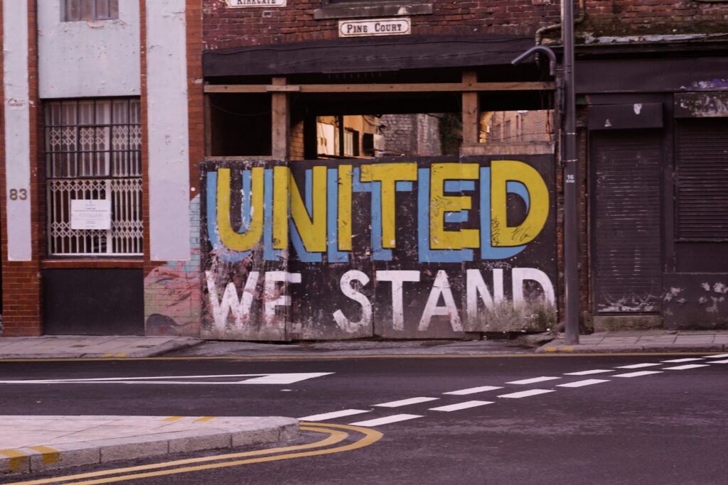 united we stand paint written on the wall near sidewalk
