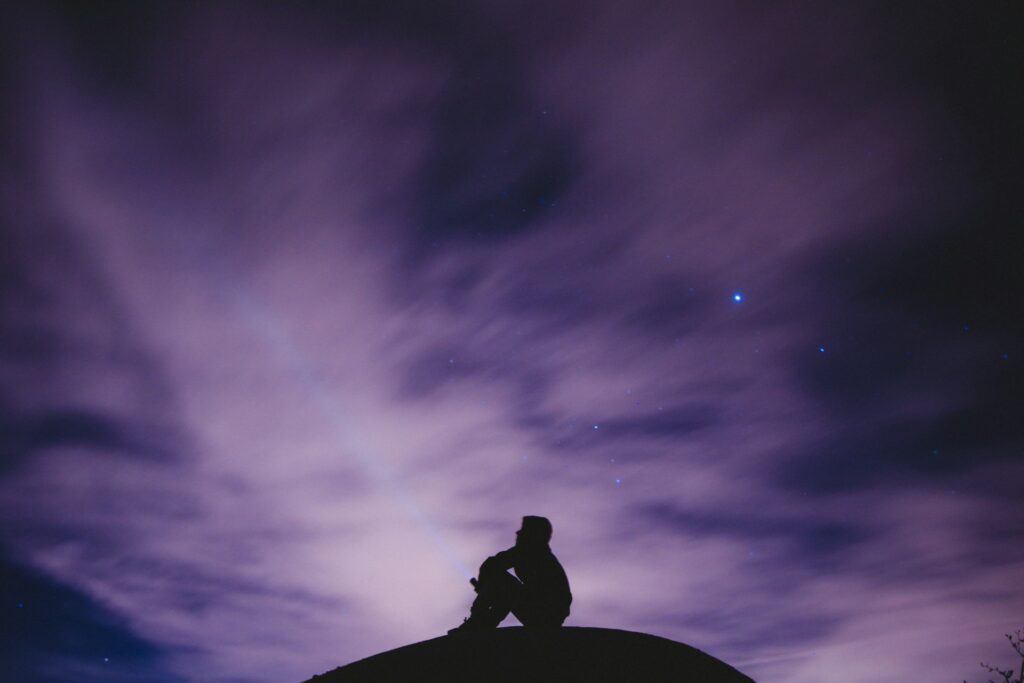 person sitting on black surface looking to sky
