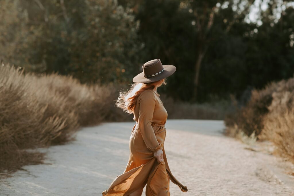 a person in a dress walking on a dirt road
