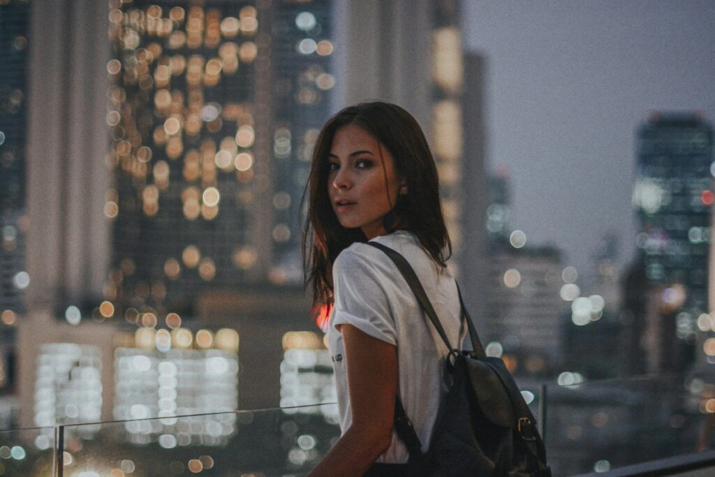 woman in white t-shirt carrying black leather backpack
