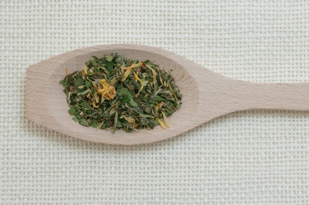 a wooden spoon filled with green tea on top of a table
