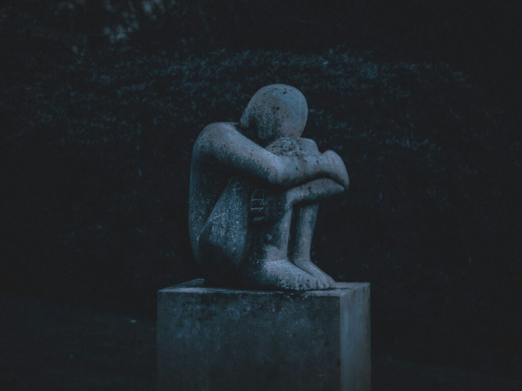 man hugging his knee statue
