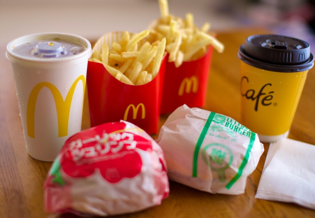 a wooden table topped with two cups of coffee and two bags of fries
