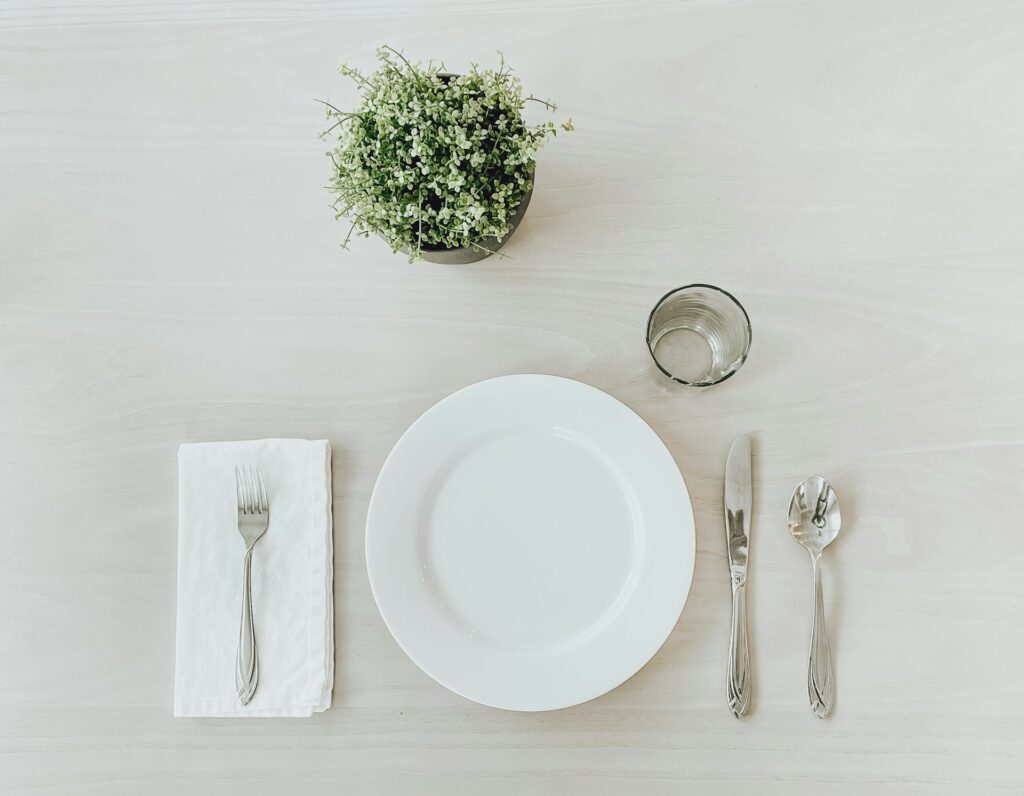 white ceramic plate beside stainless steel fork and bread knife on white table
