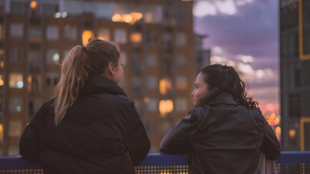 two women standing near railings
