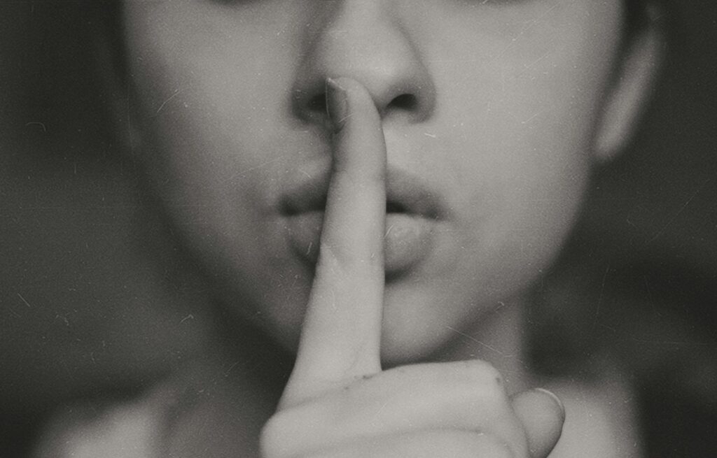 grayscale photo of woman doing silent hand sign
