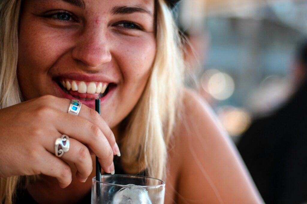 smiling woman sipping on drinking glass
