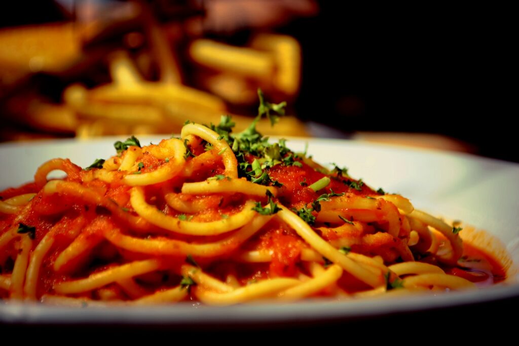 a plate of spaghetti with tomato sauce and parsley
