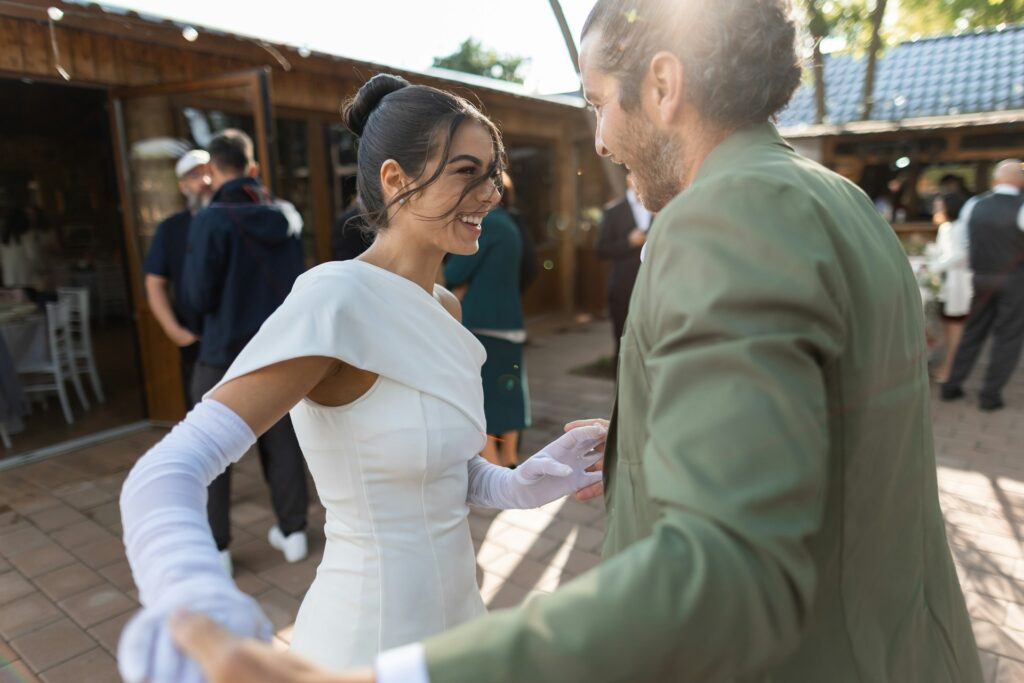 A bride and groom are dancing joyfully outdoors.