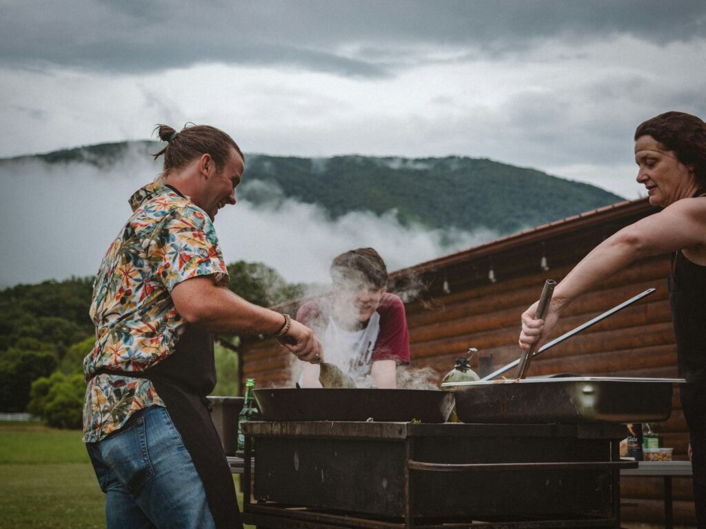 a group of people cooking on a grill outside
