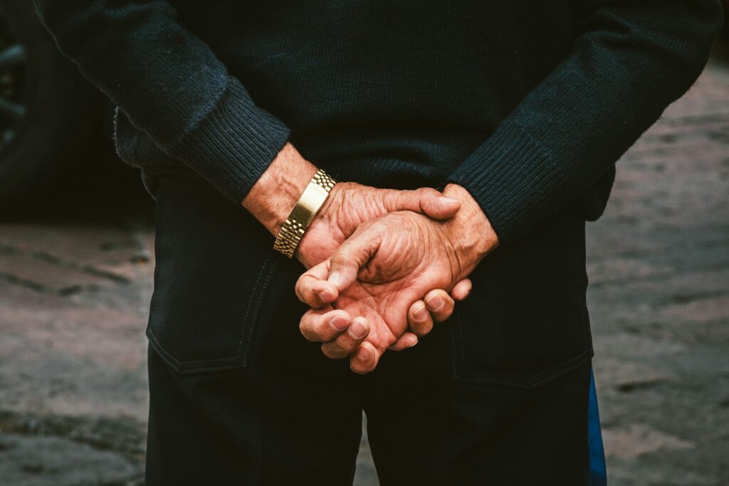 Two people holding hands in front of a car

