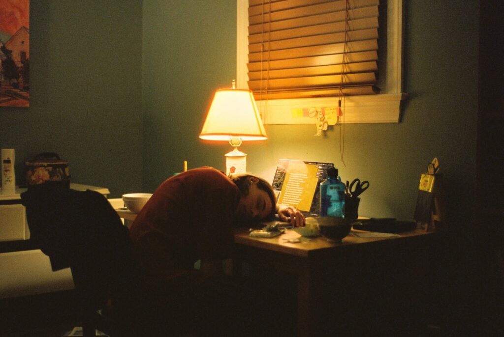 a person sitting at a desk in front of a lamp

