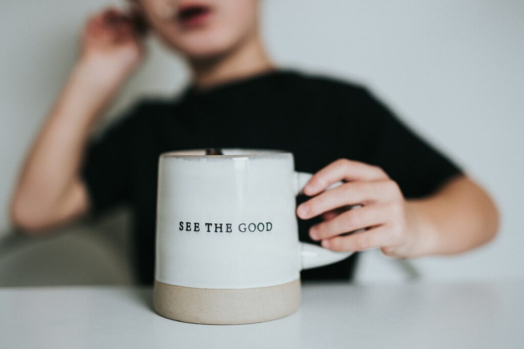 woman in black shirt holding white ceramic mug
