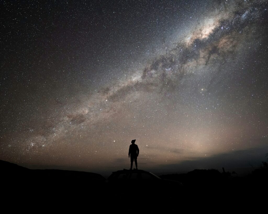 a man standing on top of a hill under a night sky

