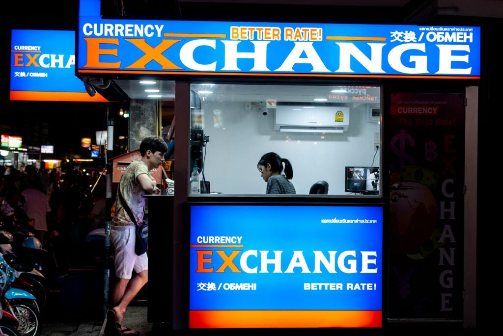 man in gray short standing near counter of currency exchange
