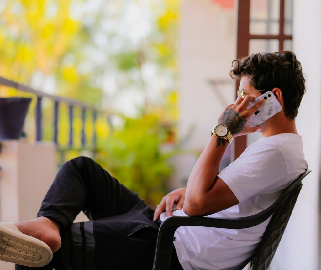 a man sitting in a chair talking on a cell phone
