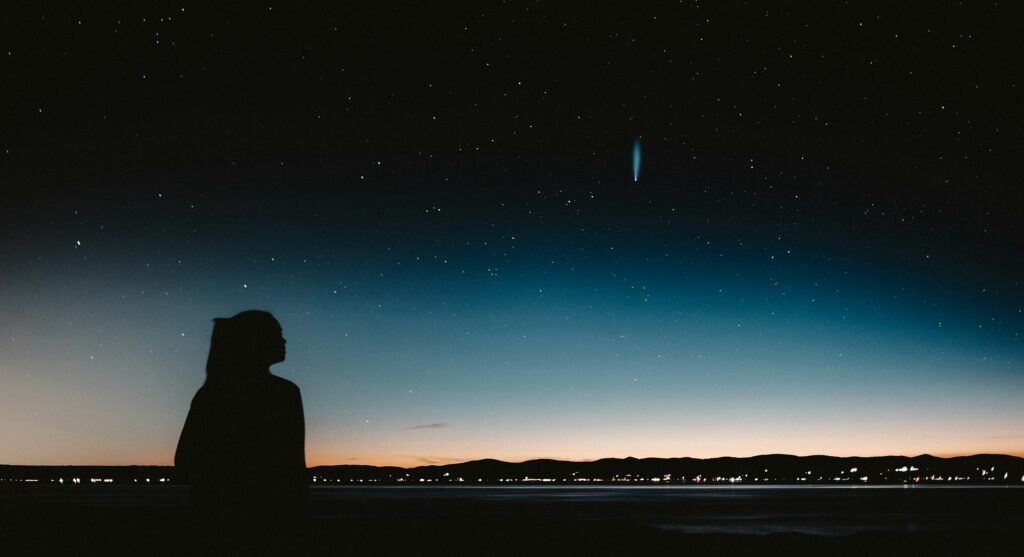 silhouette of man standing near body of water during night time

