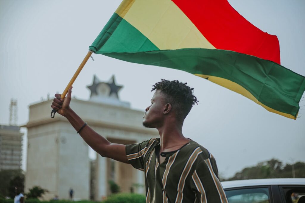 Black man with flag of Ghana on city street
