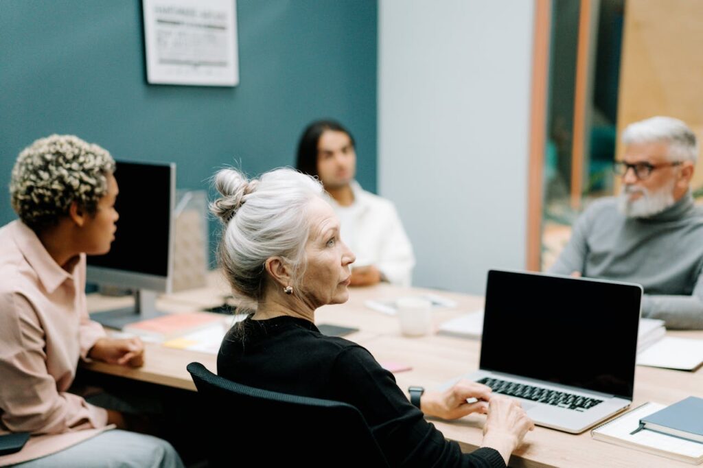 Woman in Black Sweater Sitting on Chair in Front of Macbook Pro
