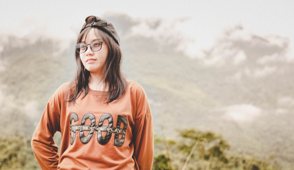 Woman Standing on Ground on Front of Mountain
