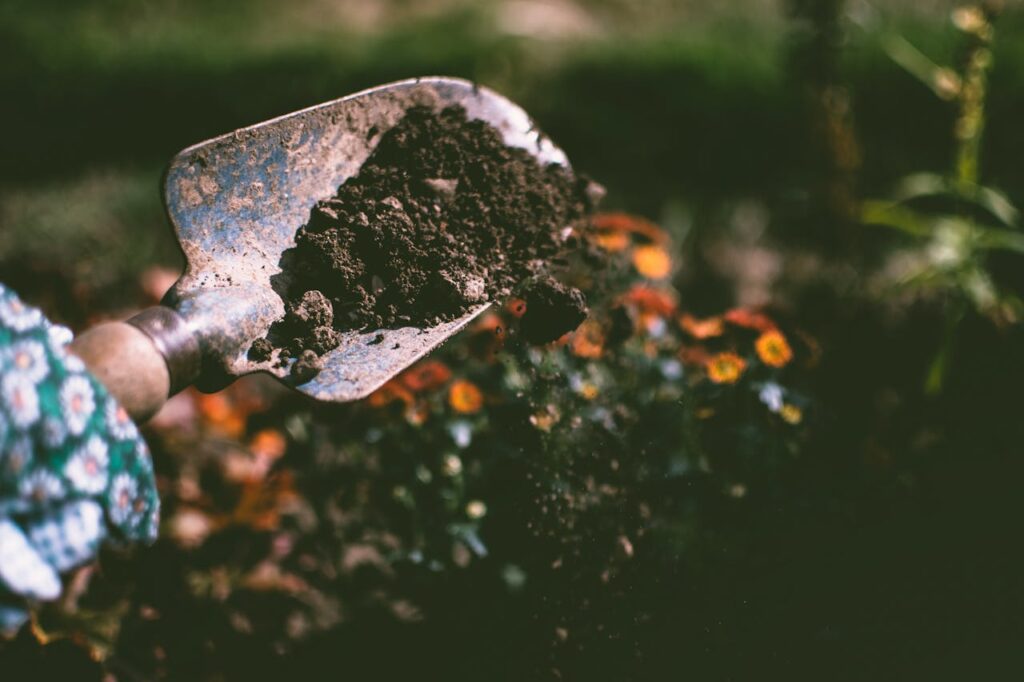 Person Digging on Soil Using Garden Shovel
