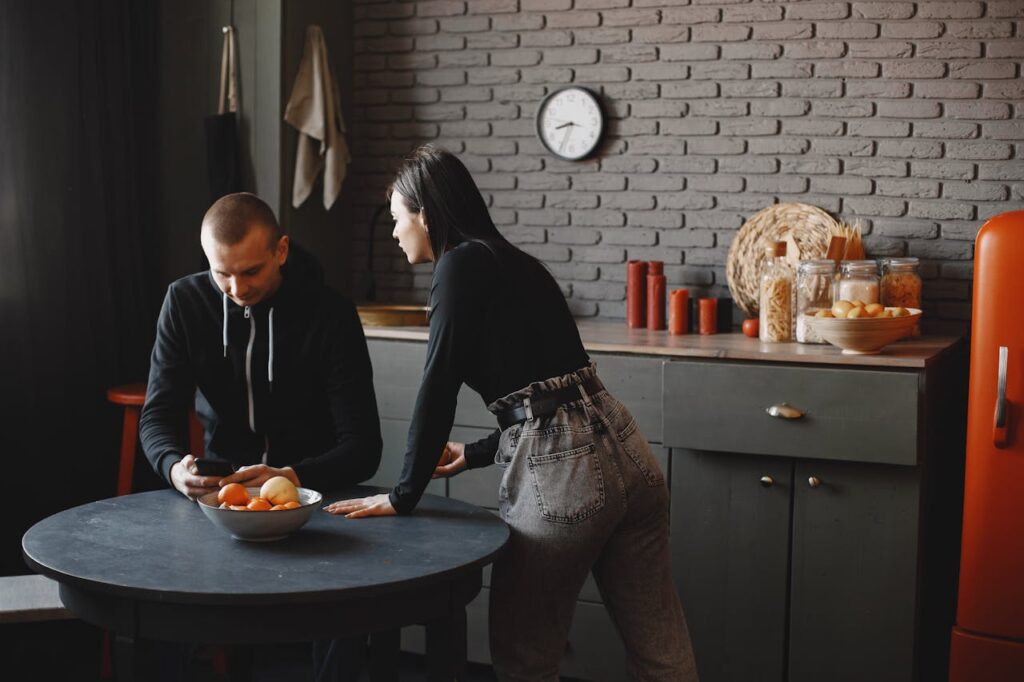 Man in a Black Hoodie Using His Phone Near a Woman