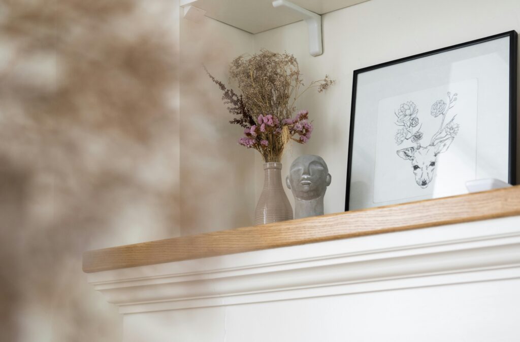 Shelf decorated with picture and dried plant
