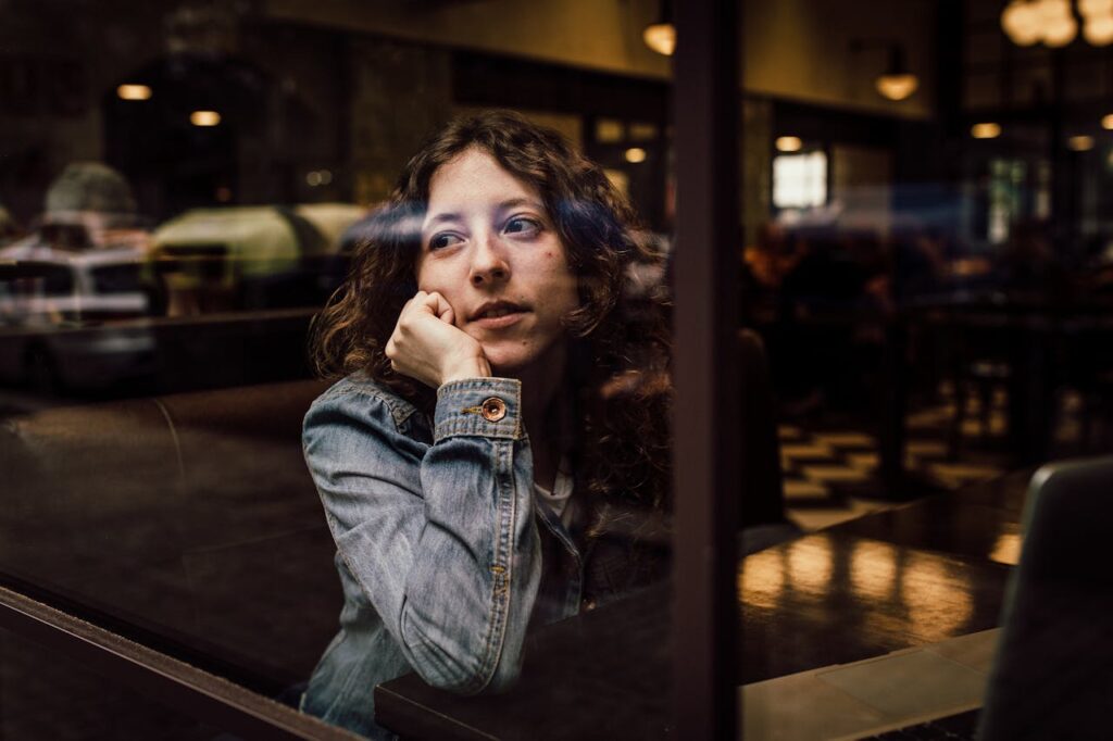 Woman Wearing Blue Denim Jacket Putting Her Right Arm on Her Cheek
