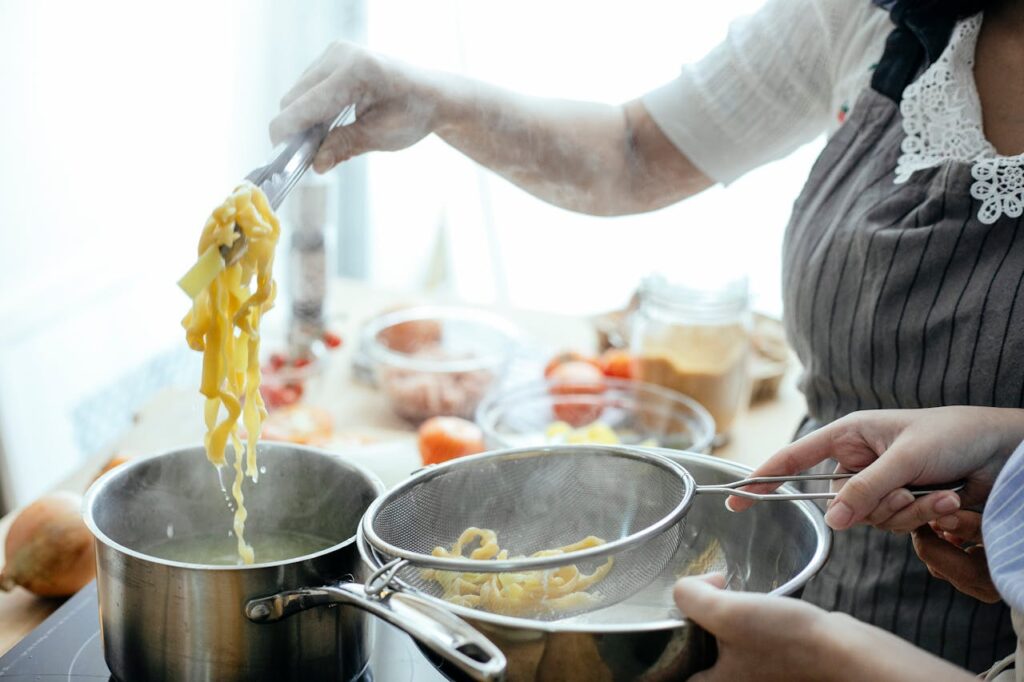 Crop women cooking pasta in kitchen
