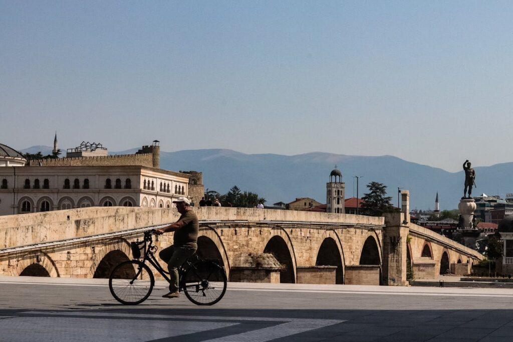 Cyclist Crosses Historic Stone Bridge in Skopje
