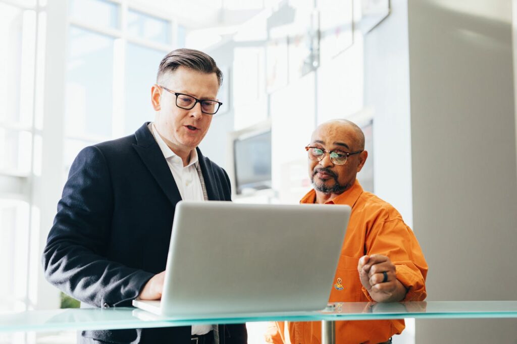 Man Using Silver Laptop Beside Another Man
