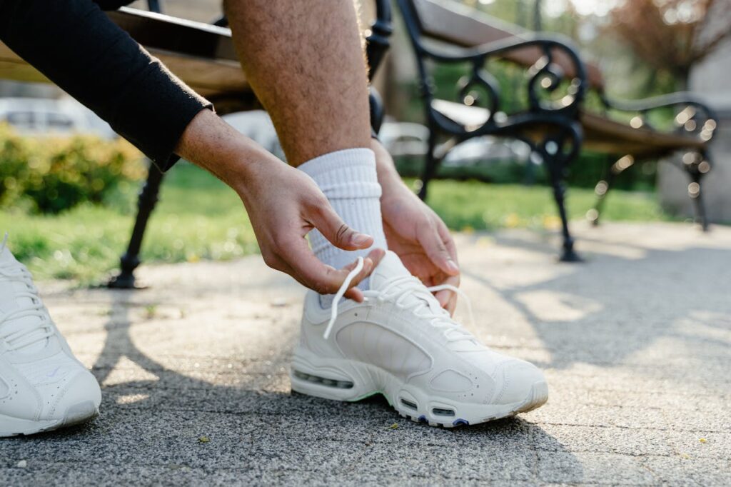 A Person in Black Long Sleeve Shirt Holding the Shoe Lace
