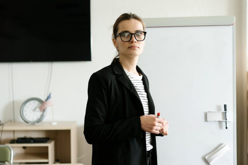 A Woman in a Black Blazer Standing beside a Whiteboard
