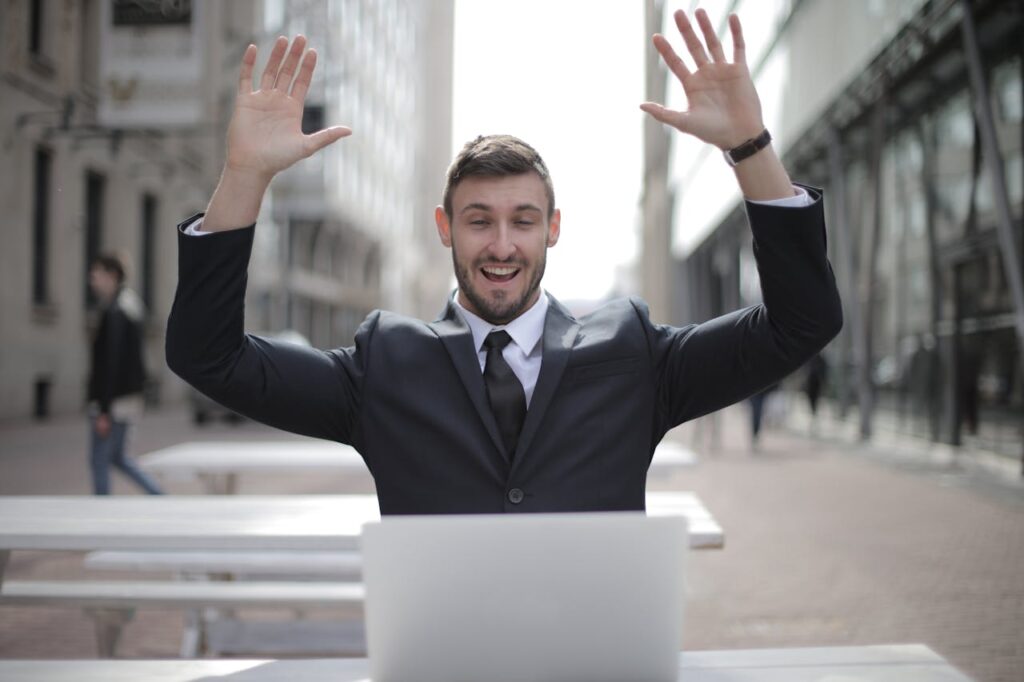 Man in Black Suit Raising Both Hands
