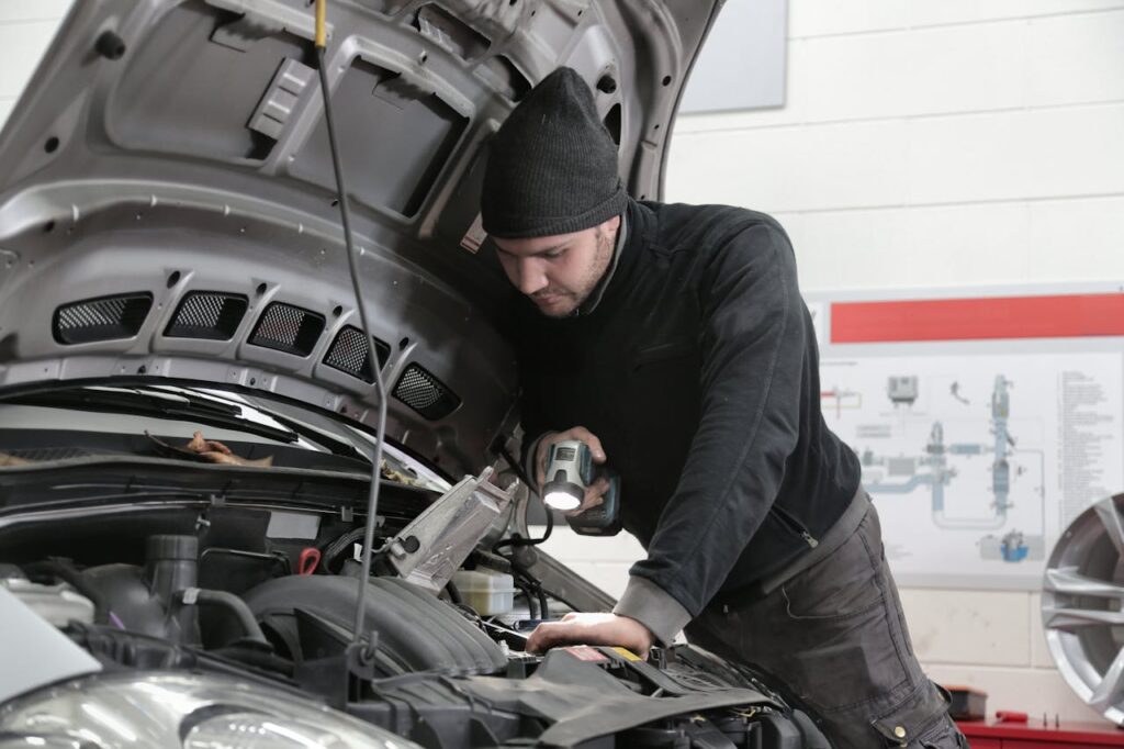 Man in Black Jacket and Black Knit Cap Inspecting Car Engine
