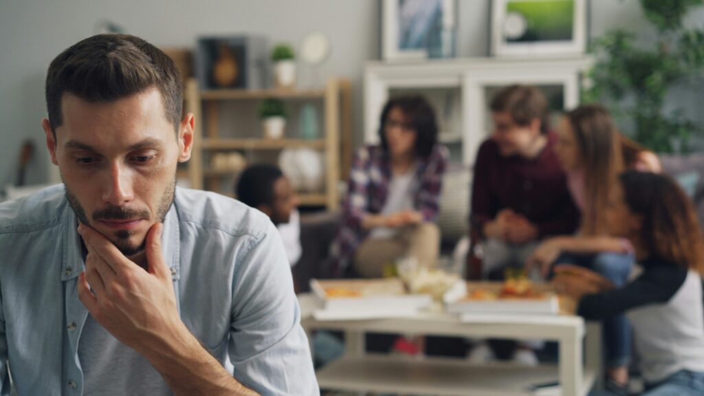 Unhappy Man Sitting At Indoor Party