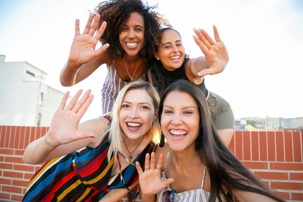 four women smiling and waving